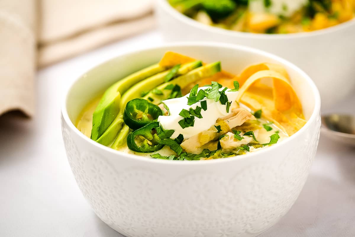 White bowl with Slow Cooker White Chicken Chili and toppings
