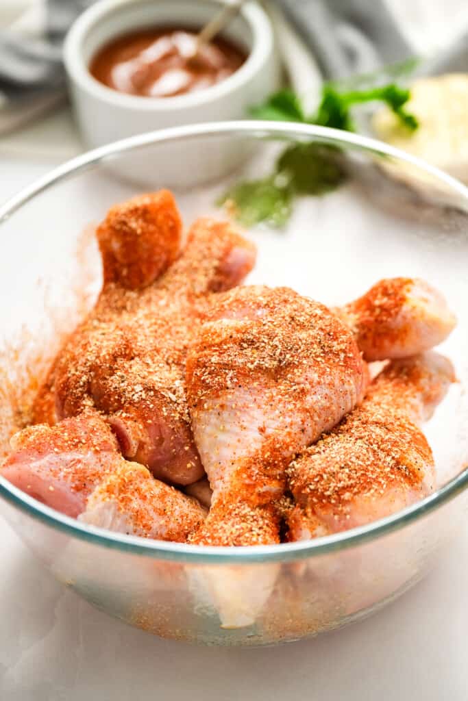 Chicken legs with rub on them in glass bowl