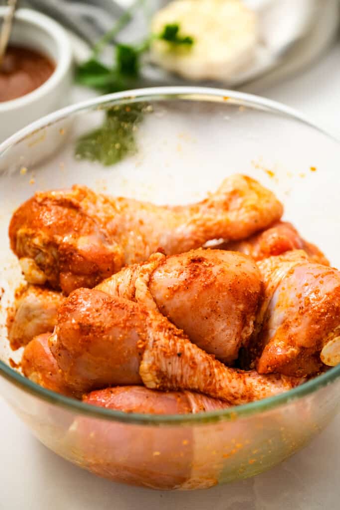 Seasoned chicken legs in glass bowl