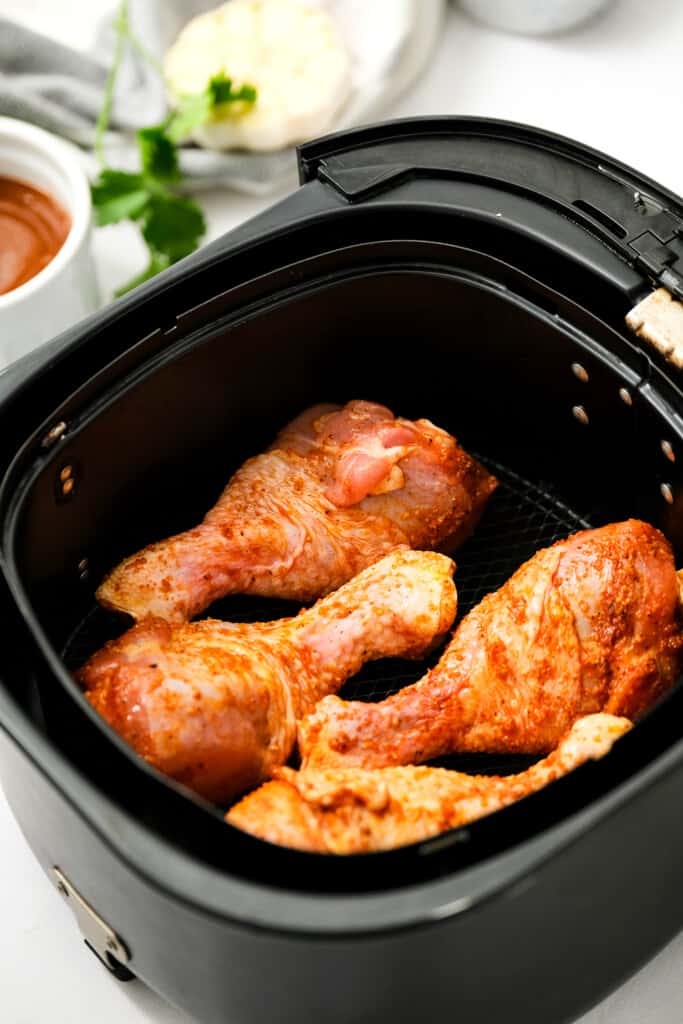 Air Fryer with seasoned chicken legs in it