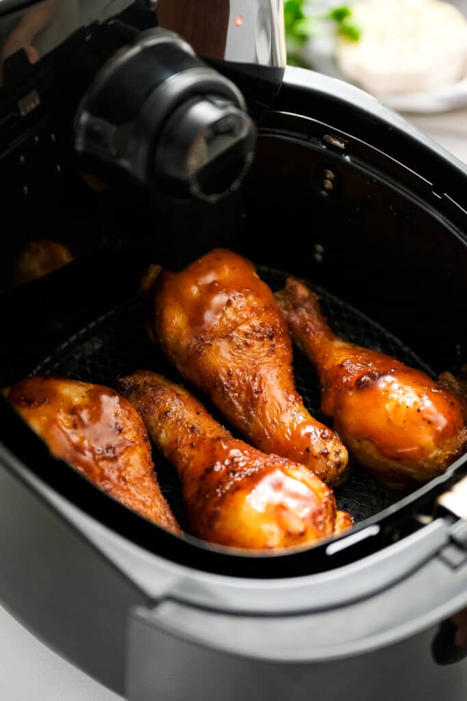 Air Fryer basket with BBQ Chicken legs in it