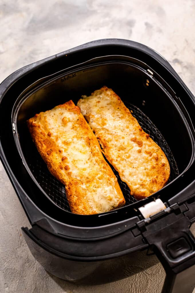 Air Fryer basket with cooked cheesy garlic bread