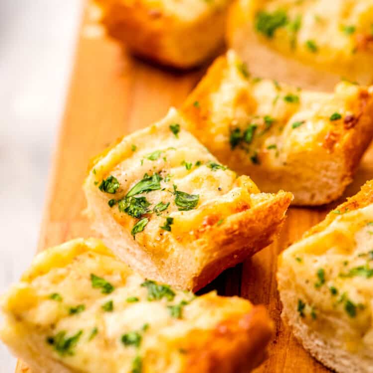 Slice of cheesy garlic bread on a wooden platter