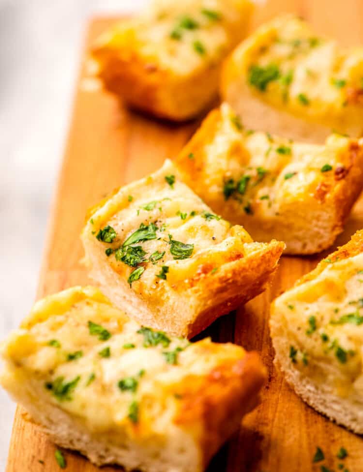 Slice of cheesy garlic bread on a wooden platter
