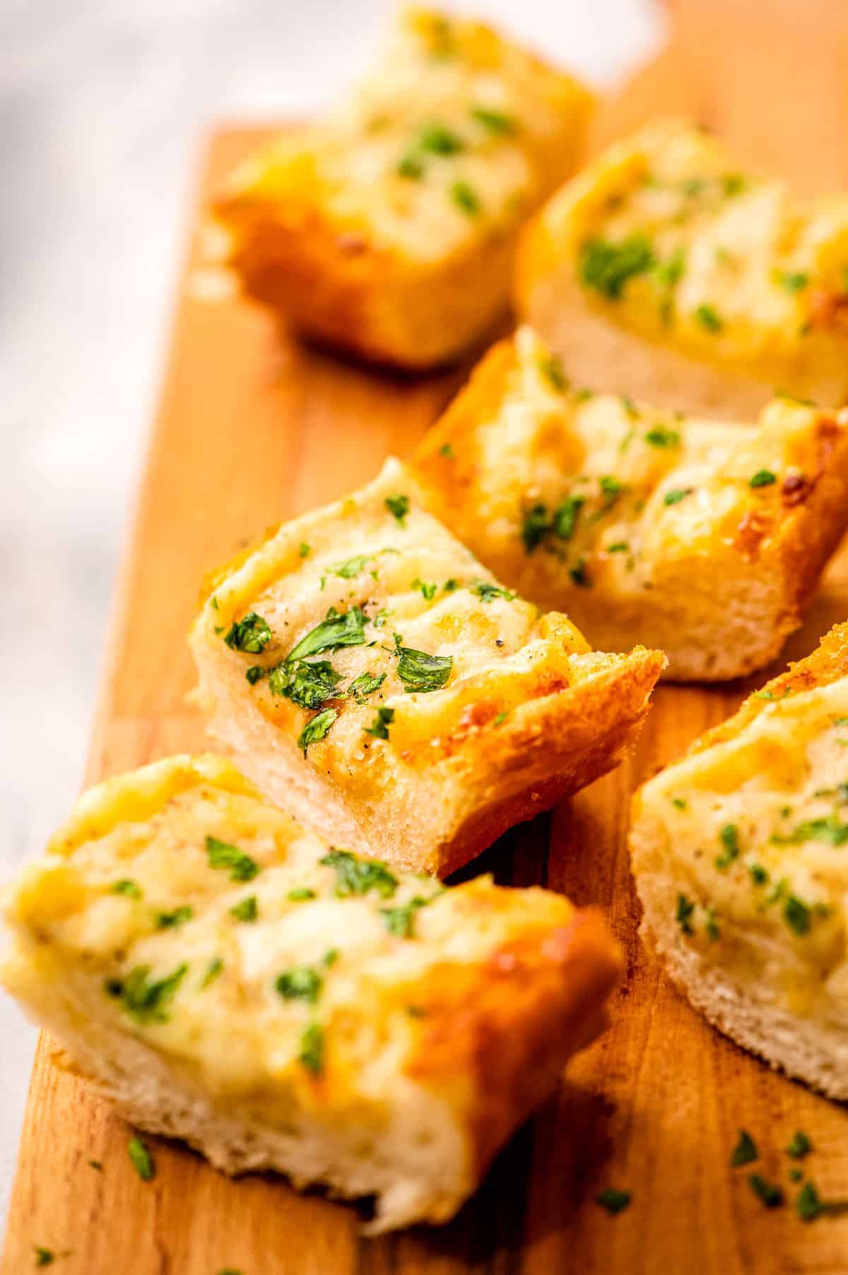 Slice of cheesy garlic bread on a wooden platter