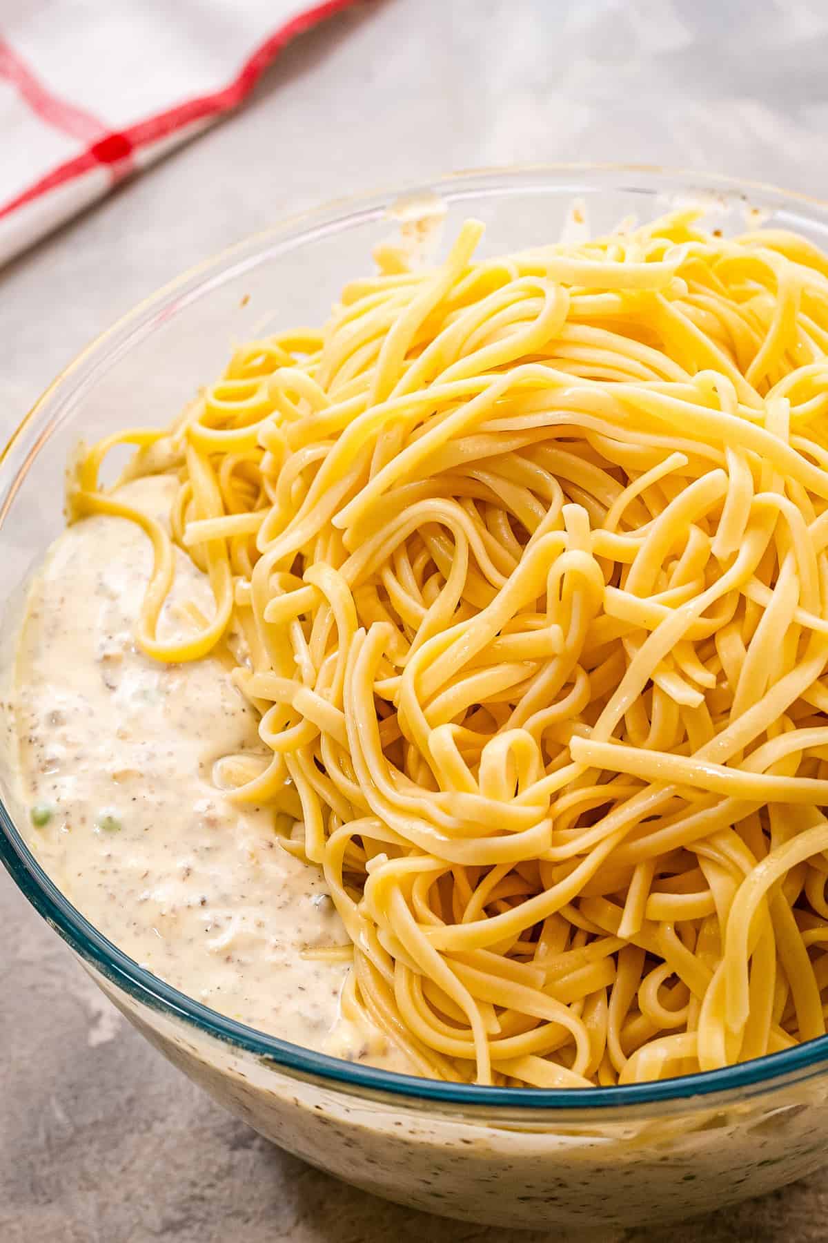 Noodles added to creamy tetrazzini mixture in bowl