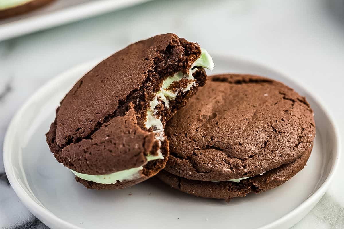 Chocolate Mint Sandwich Cookies with one bite taken out of it on white plate