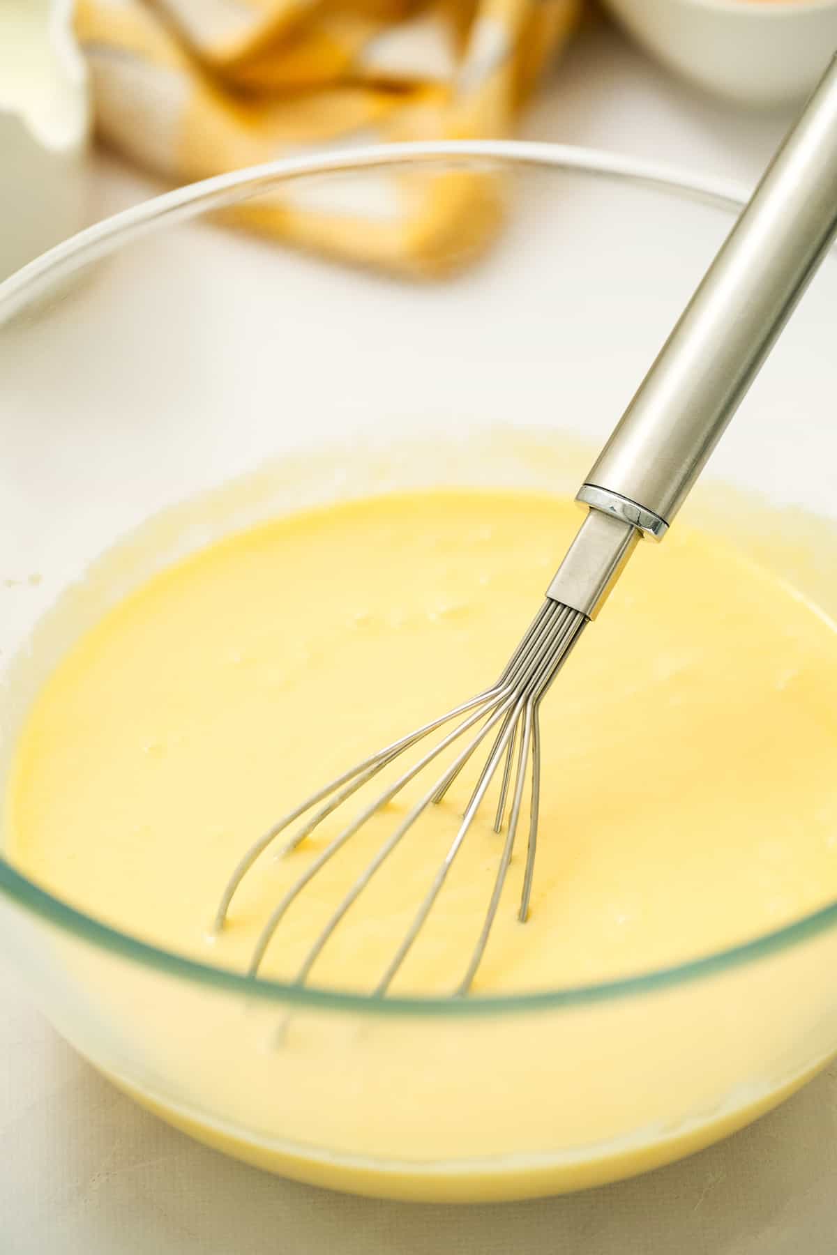 Glass bowl with wet ingredients and whisk