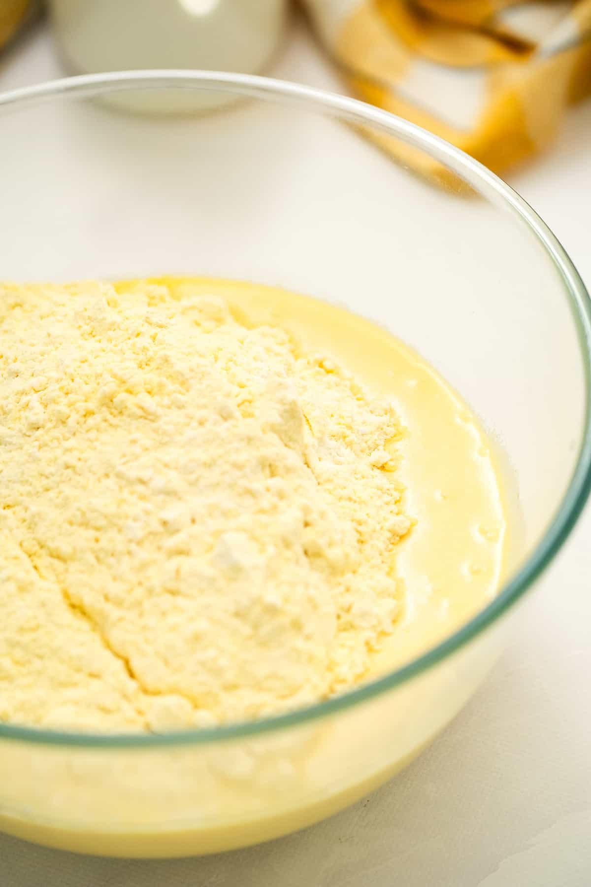 Glass bowl with wet ingredients being added to dry ingredients for cornbread