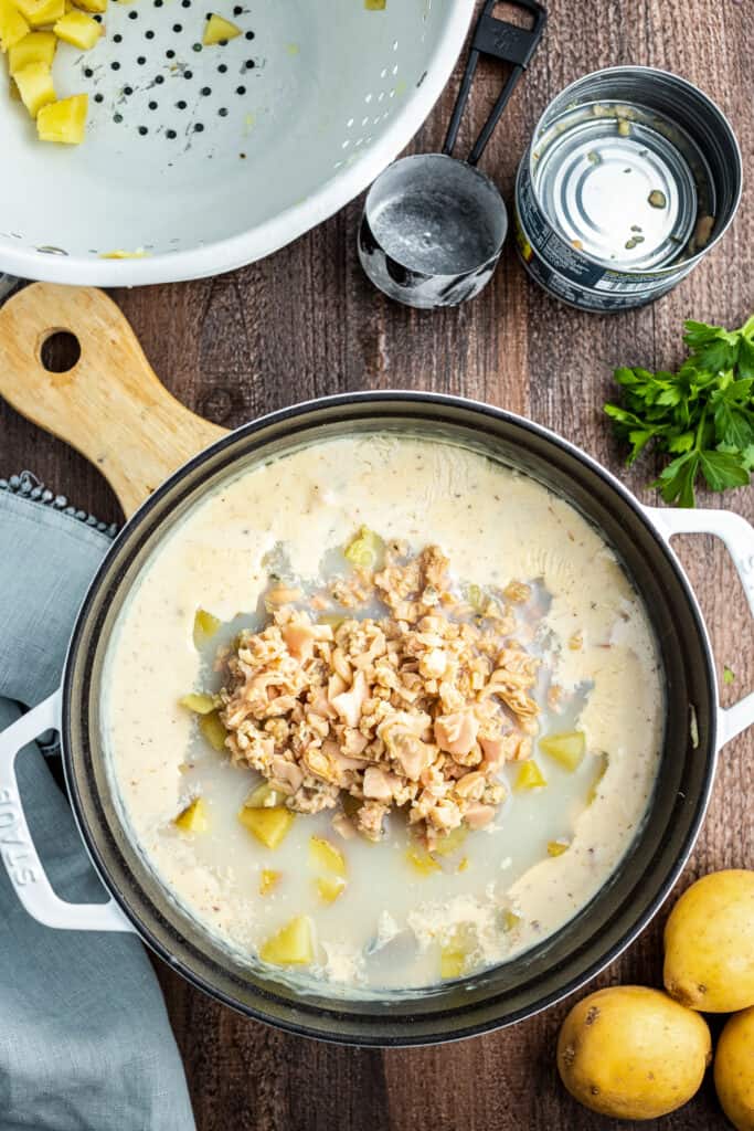 Large pot with creamy base for soup and clams on top before stirring