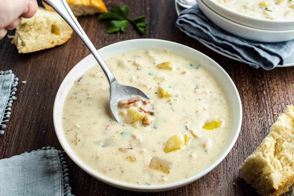 Spoon taking a bit out of a bowl of New England Clam Chowder