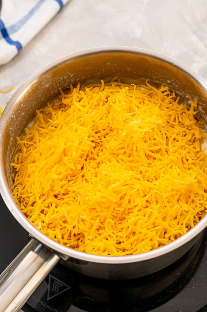 Shredded cheese in saucepan to make cheese sauce