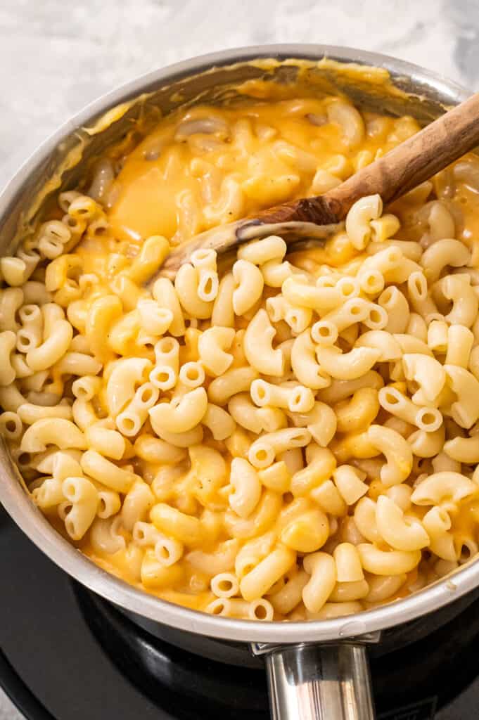 Stirring elbow mac and cheese in cheese sauce