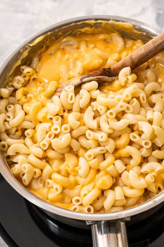 Stirring elbow mac and cheese in cheese sauce