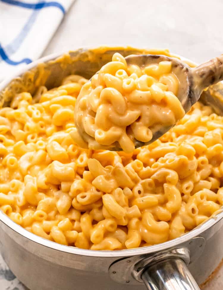 Wooden spoon scooping mac and cheese out of saucepan