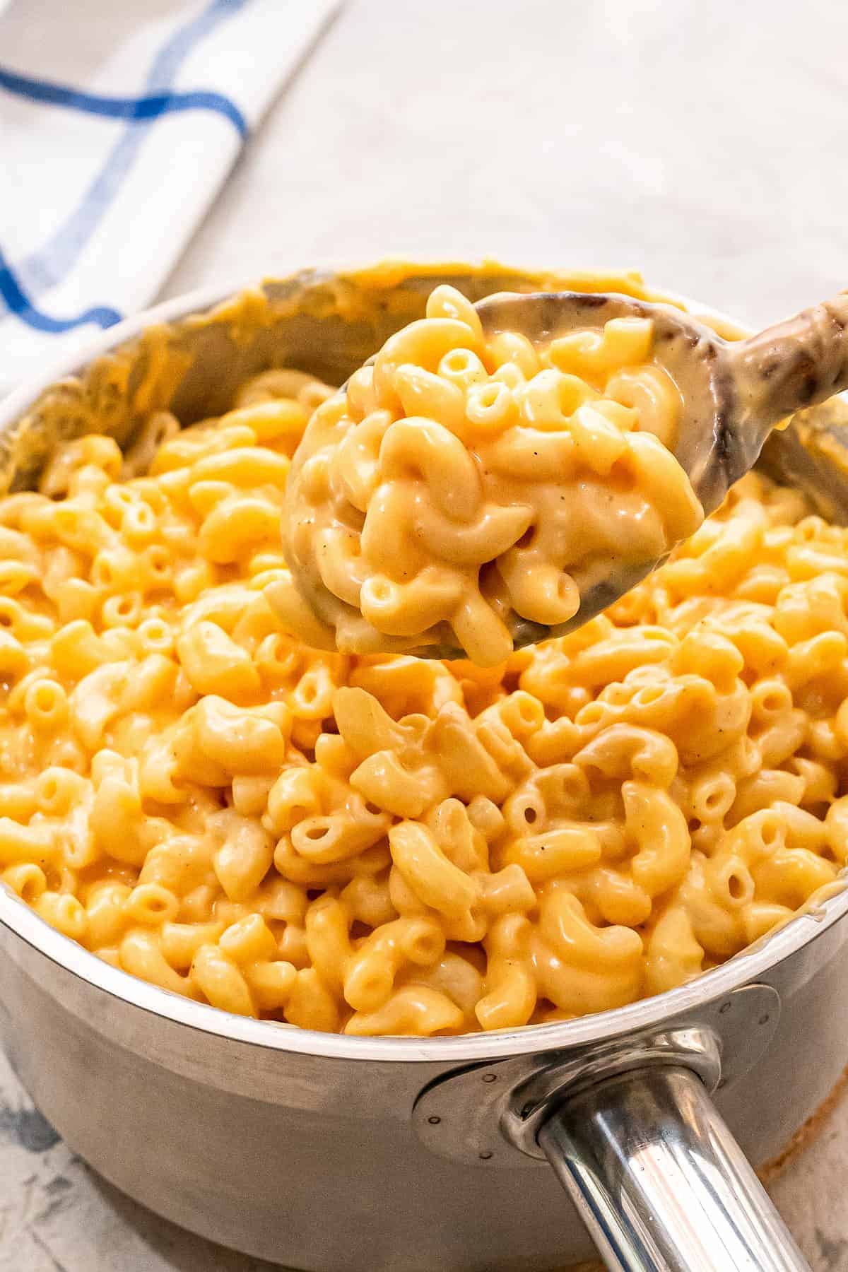 Wooden spoon scooping mac and cheese out of saucepan