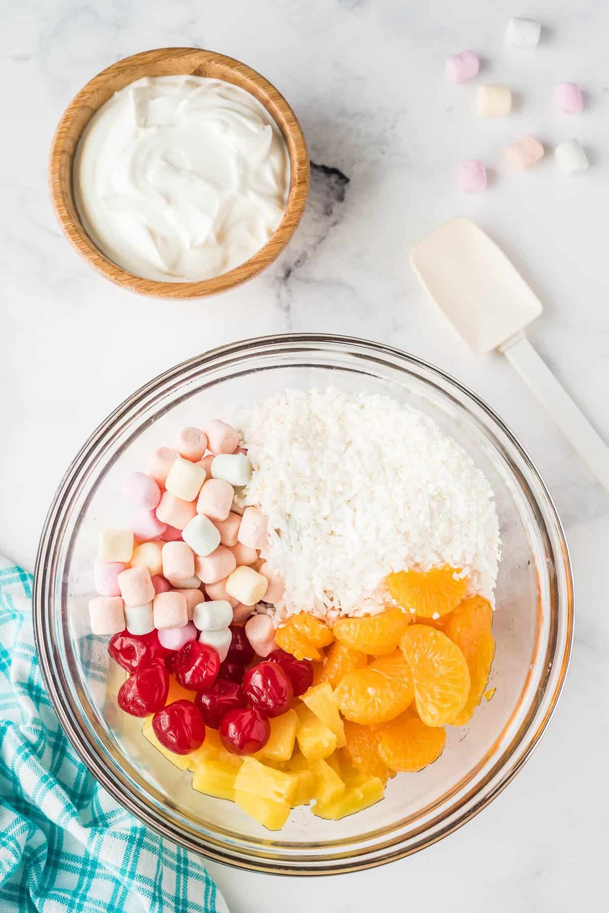 Overhead image of glass bowl with ingredients for Ambrosia salad before mixing