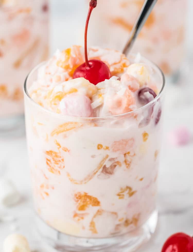 Small glass with Ambrosia Salad topped with maraschino cherry