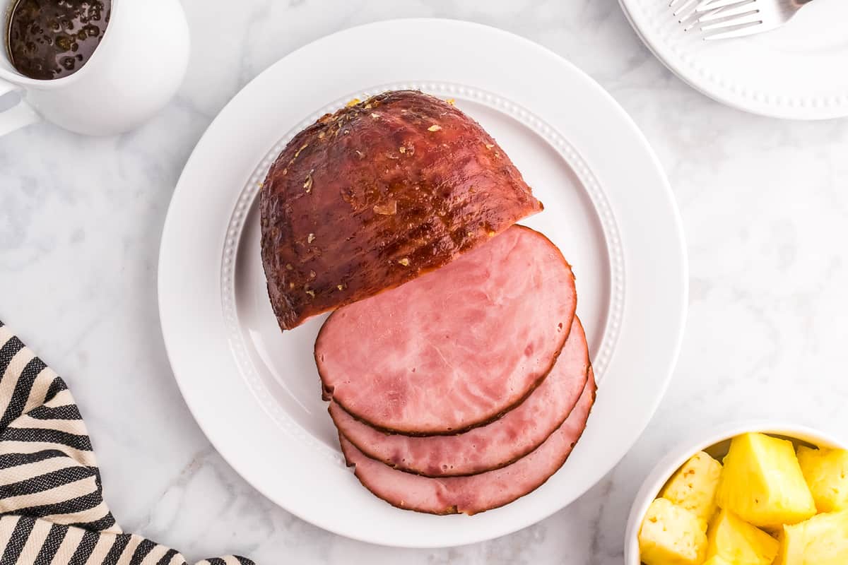 Overhead image of sliced ham on white plate with pineapple glaze