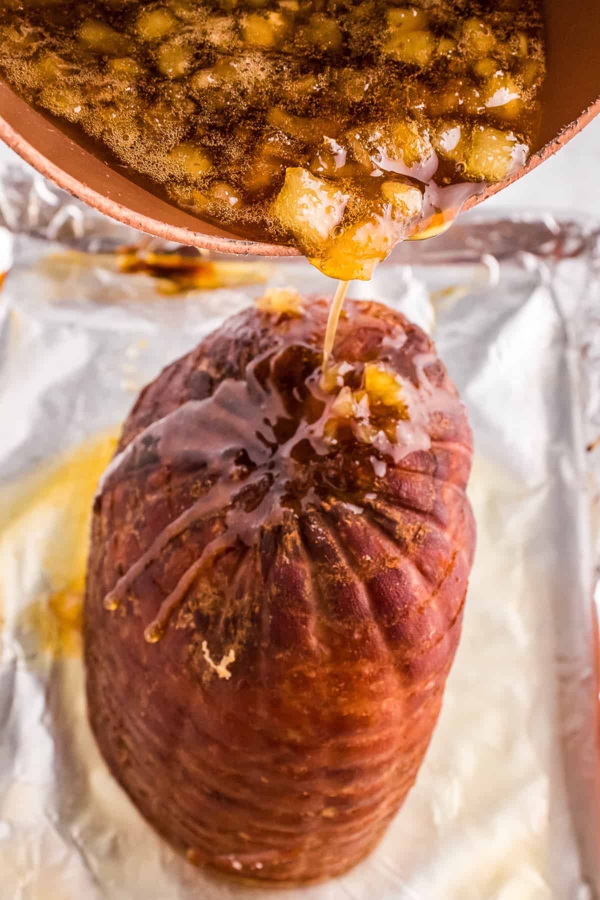 Pouring pineapple glaze of baked ham