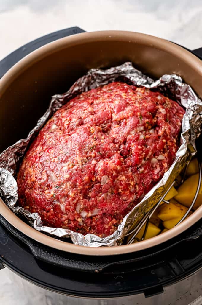 Instant Pot with cubed potatoes and meatloaf in tinfoil pocket
