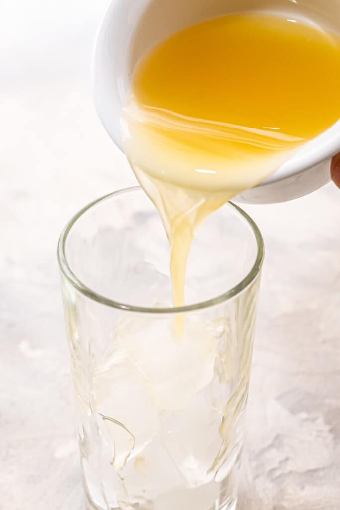 Pouring pineapple juice into ball glass