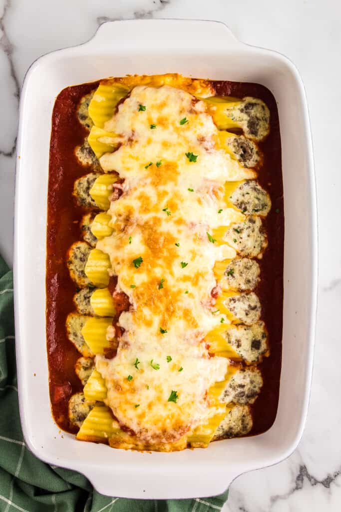 White casserole dish with stuffed manicotti pasta topped with cheese after baking