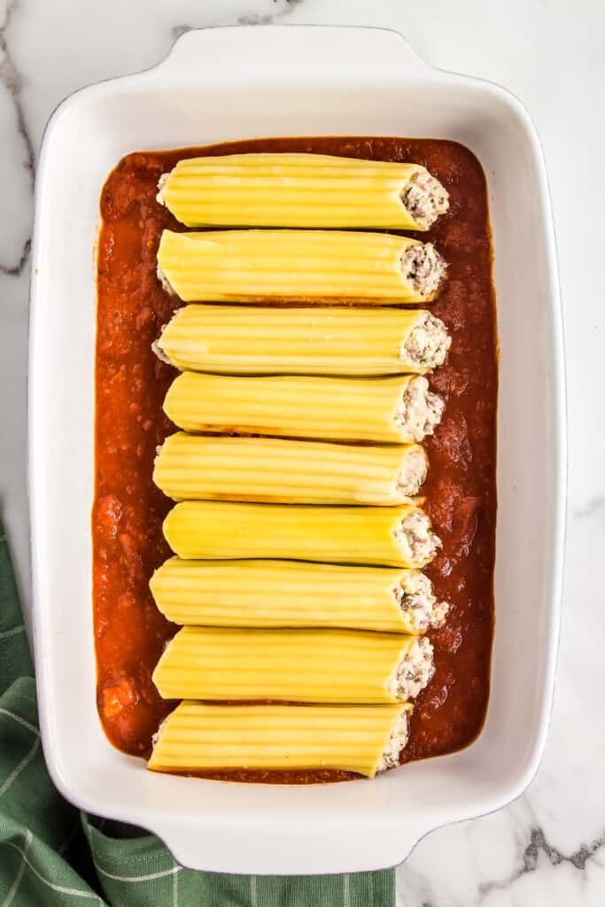 White casserole dish with stuffed manicotti pasta