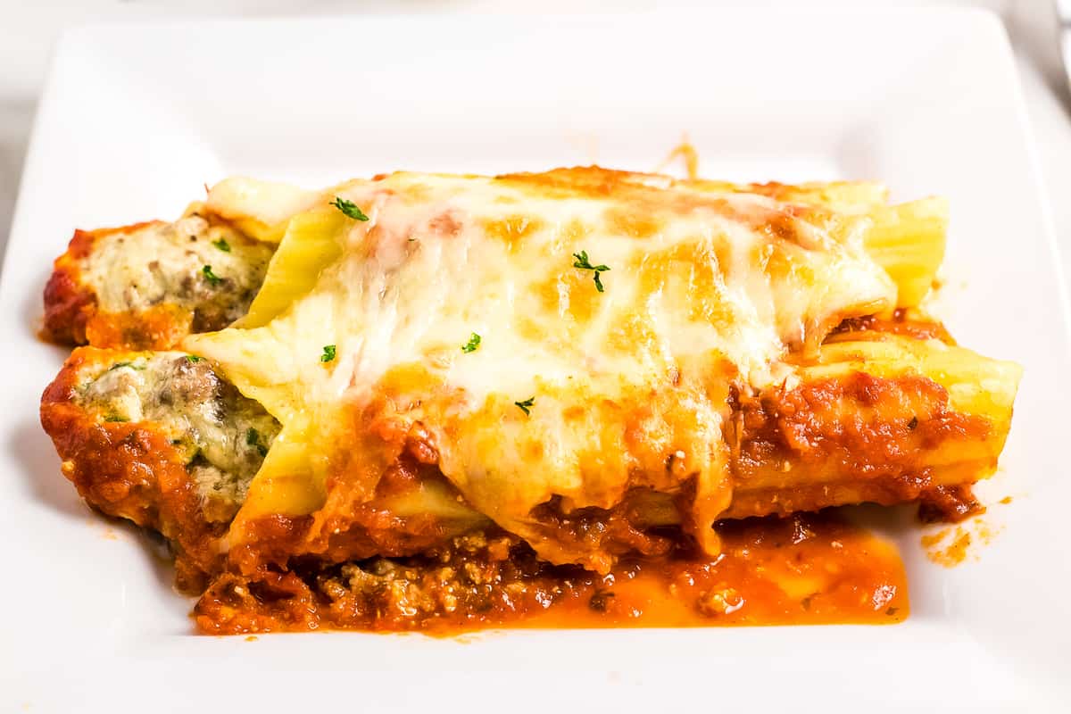 White dish with two manicotti noodles on it
