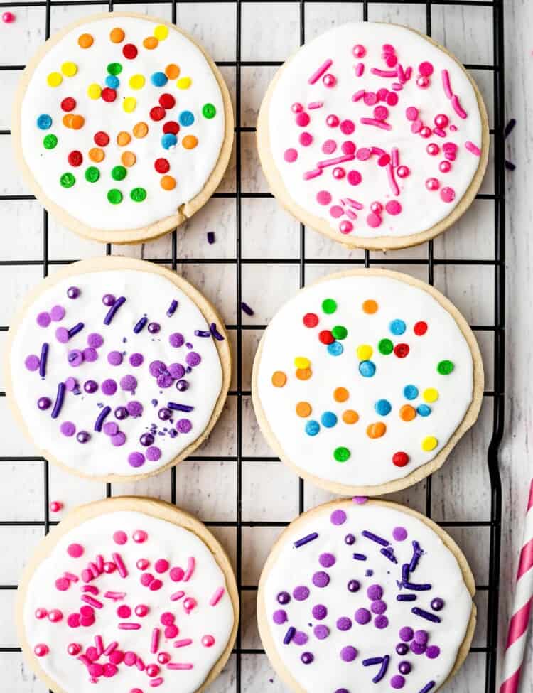 Round sugar cookies on baking rack decorated with royal icing and sprinkles