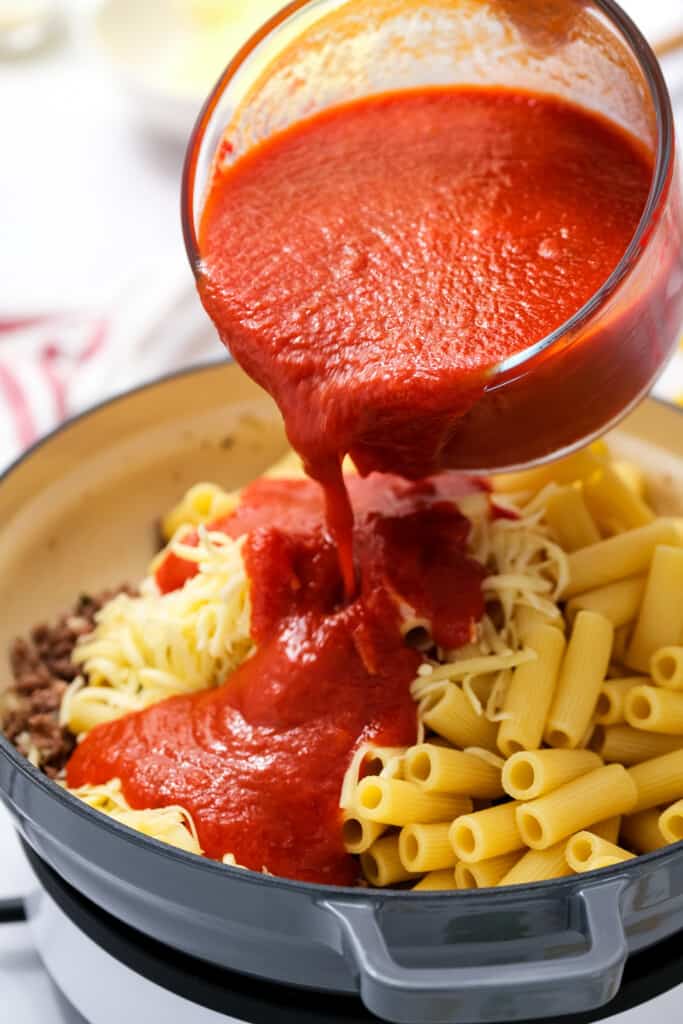 Pouring marinara sauce over pasta and ground beef