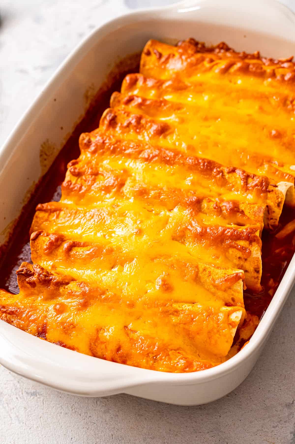 White casserole dish with ground beef enchiladas