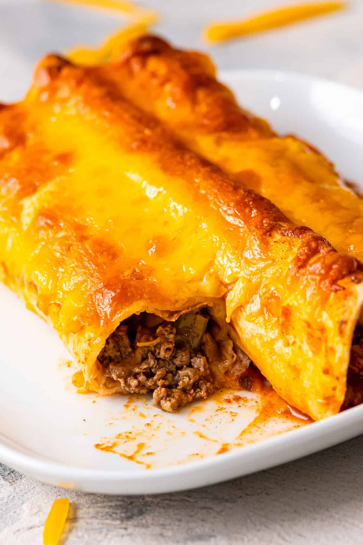 White plate with beef enchiladas cut open