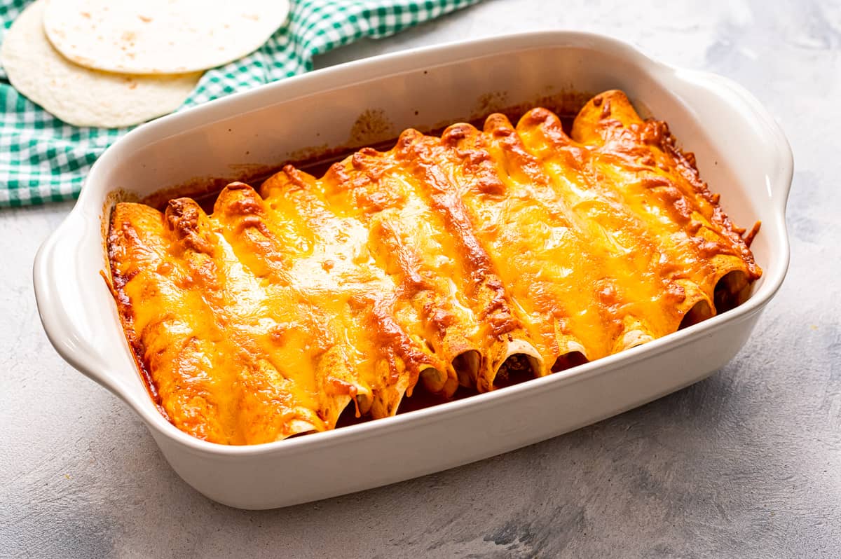 White casserole dish with baked beef enchiladas