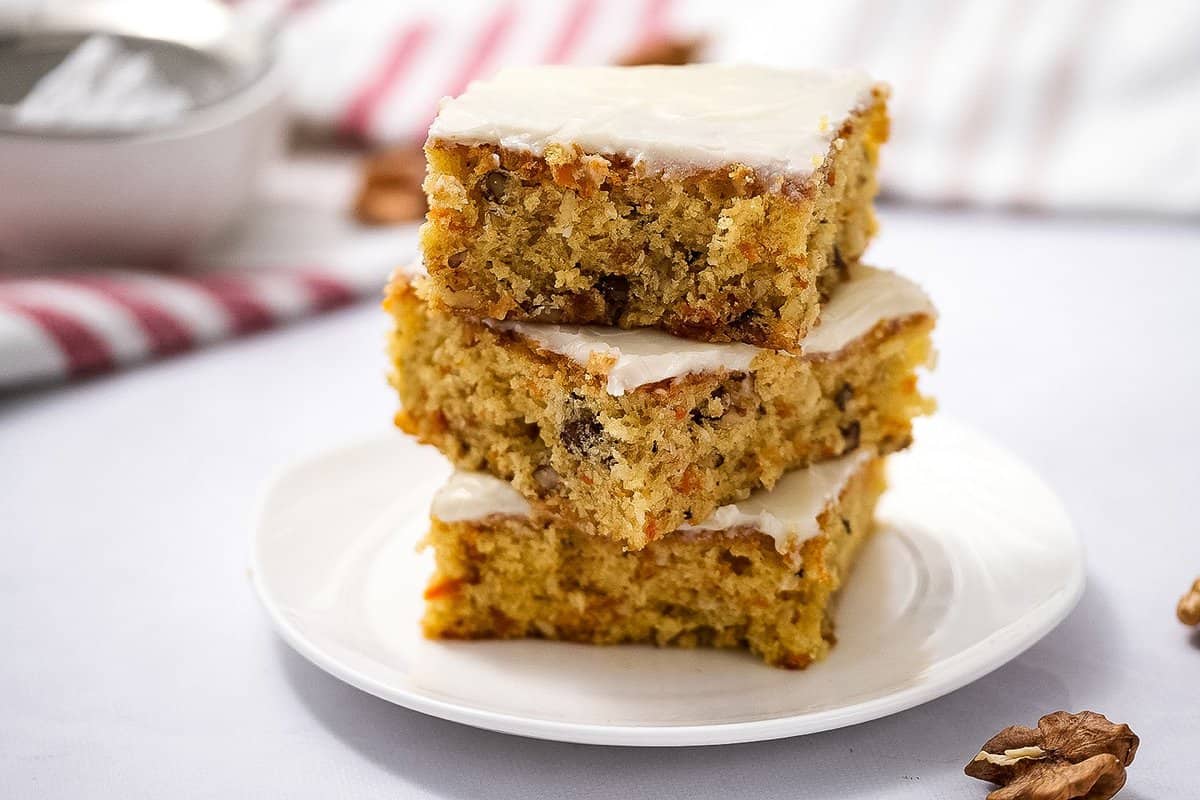 Carrot cake bars sliced and stacked on top of each other on white plae