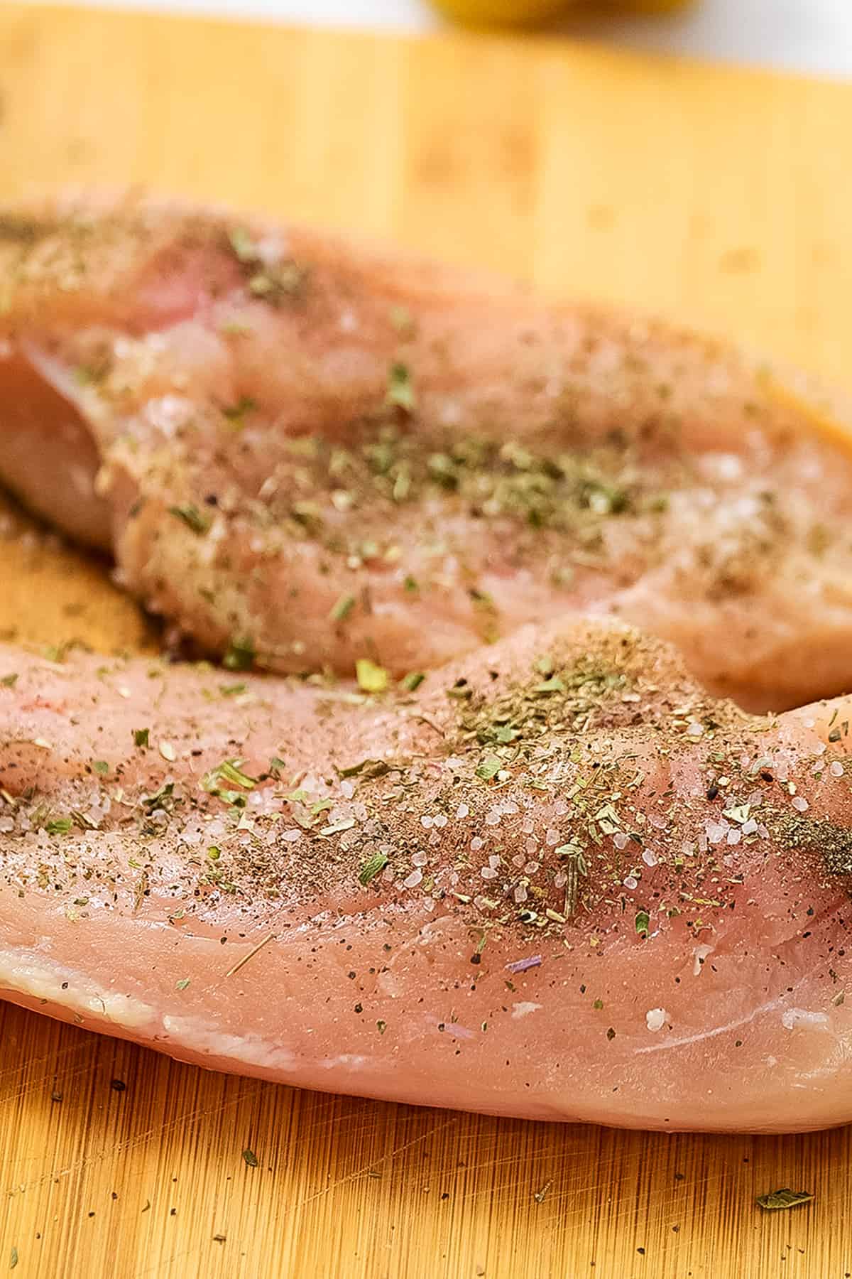 Seasoned chicken breasts on wood cutting board