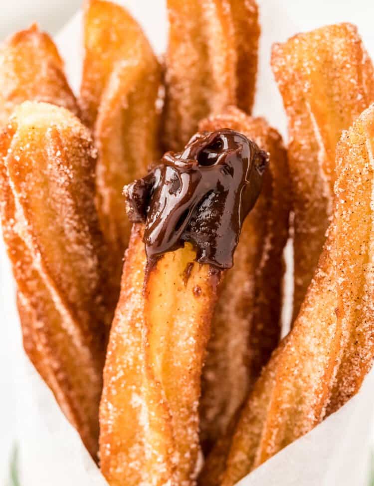 Close up of fried churro dipped in chocolate sauce