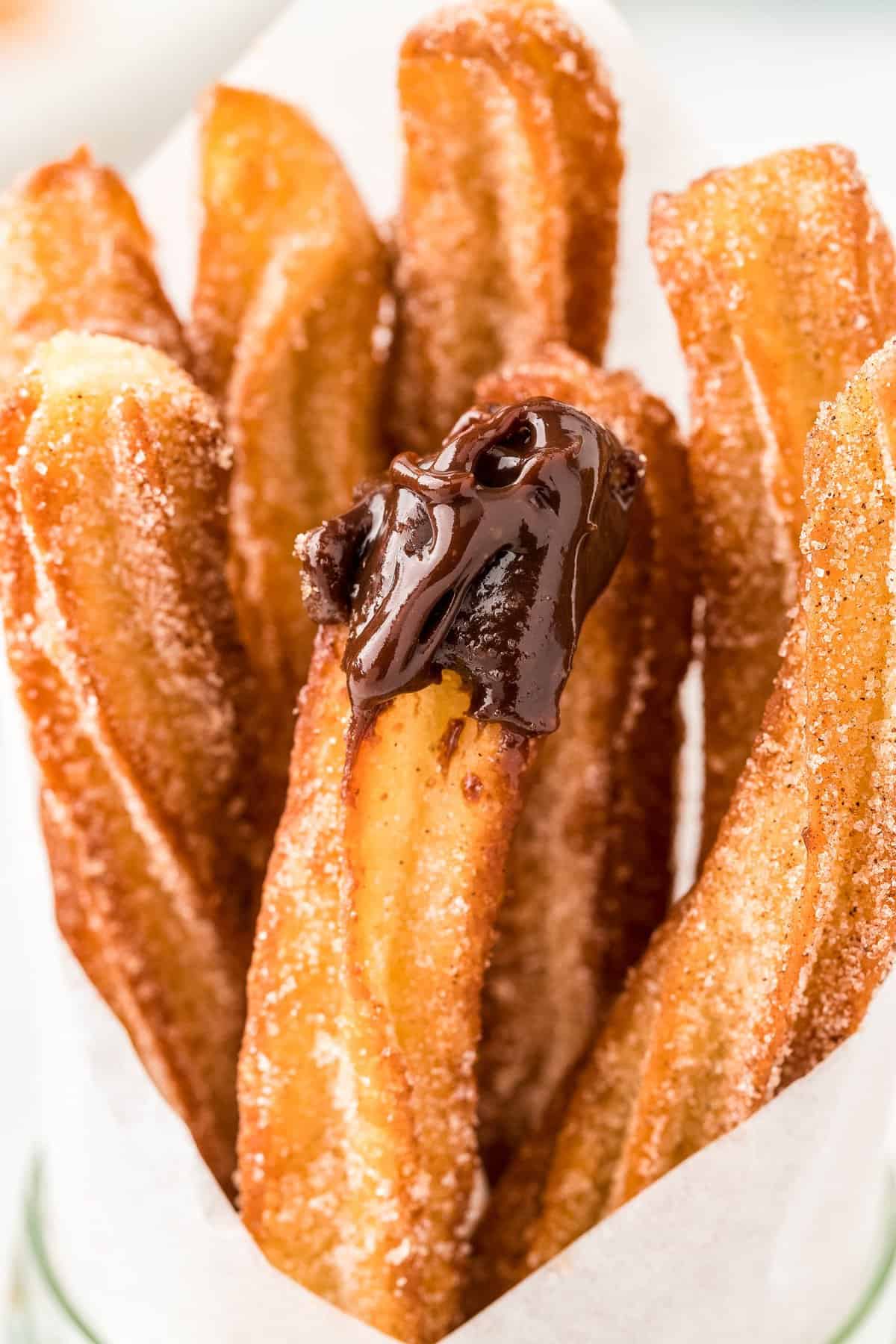 Close up of fried churro dipped in chocolate sauce