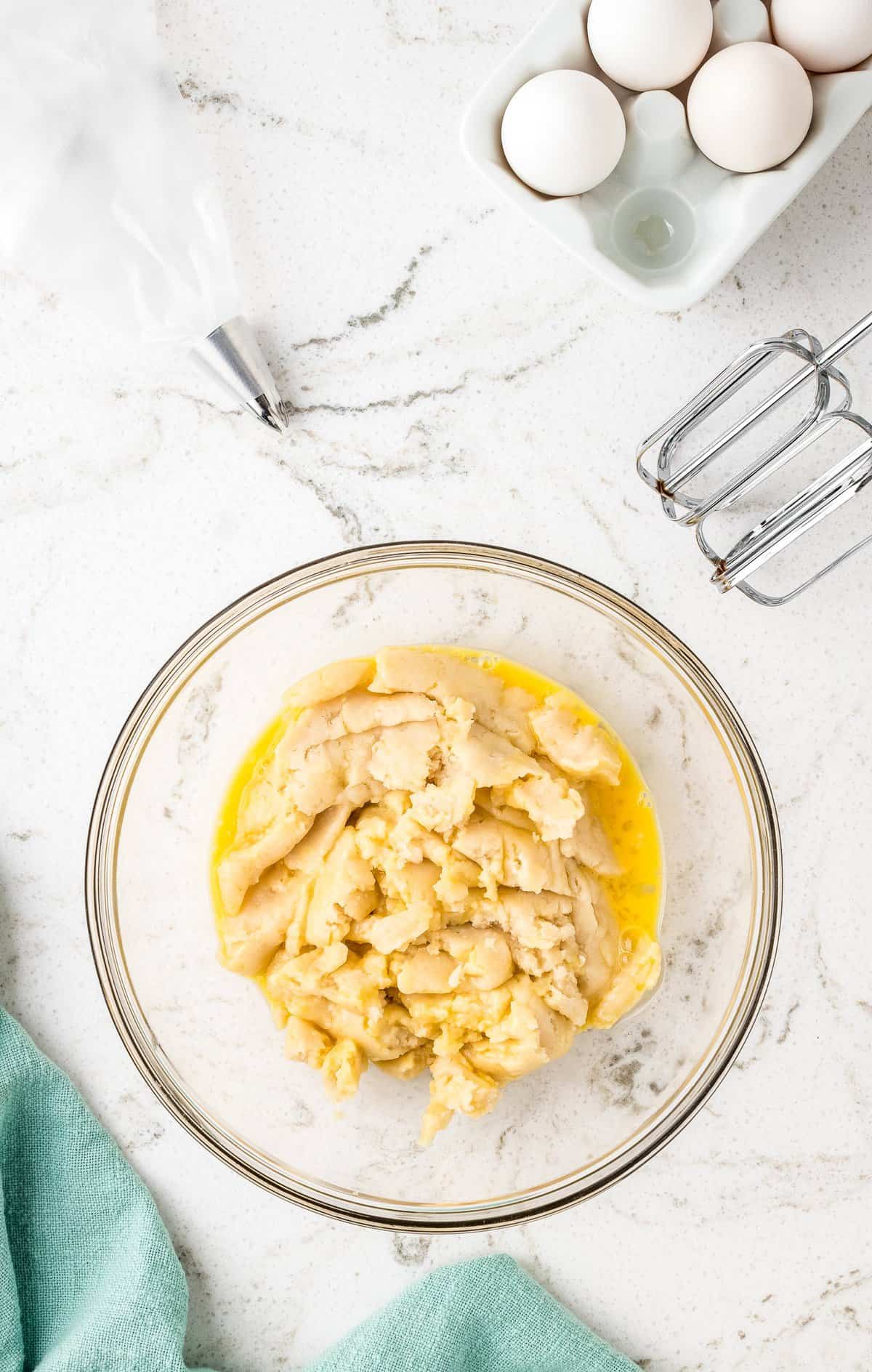 Overhead image of churro dough and egg in mixing bowl