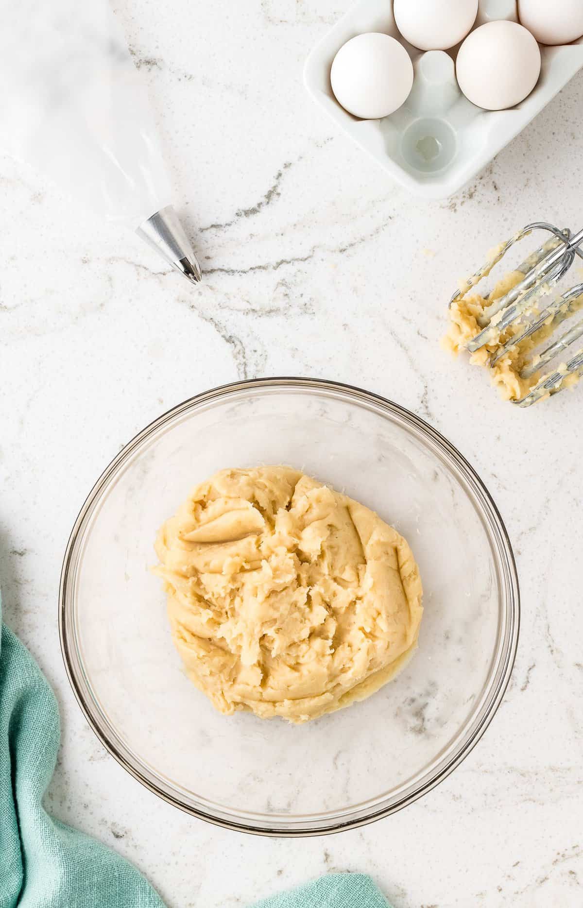 Overhead image of raw churro dough in glass bowl