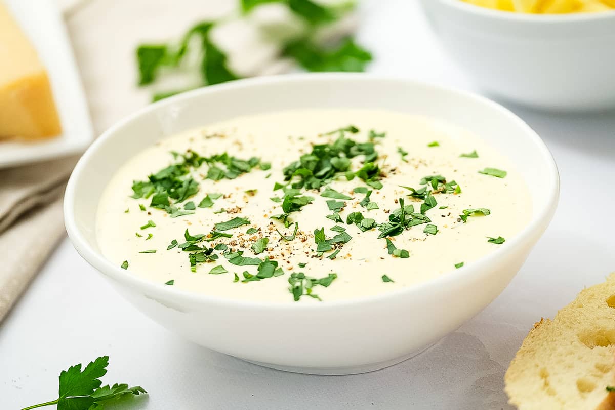 Bowl of alfredo sauce with chopped parsley garnish