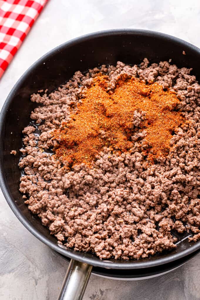 Skillet with ground beef and taco seasoning on top