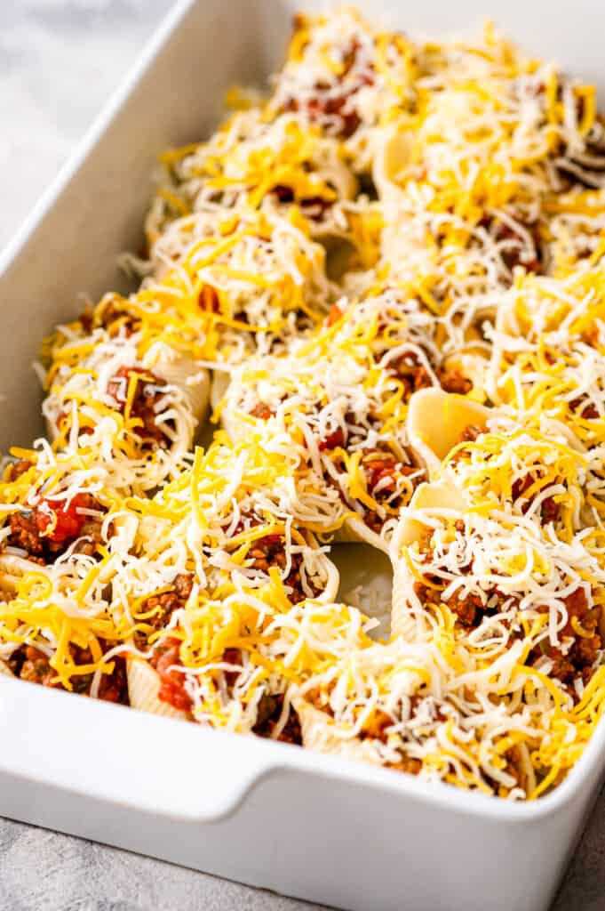 White casserole dish with stuffed taco shells before baking