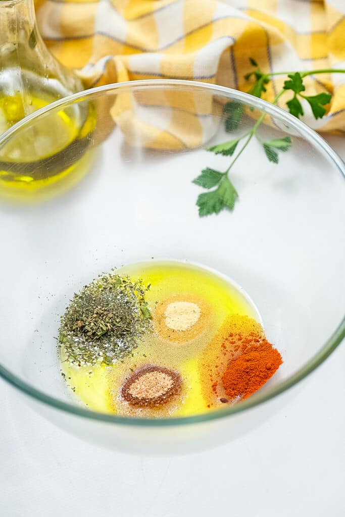 Glass bowl with oil and seasonings before mixing together