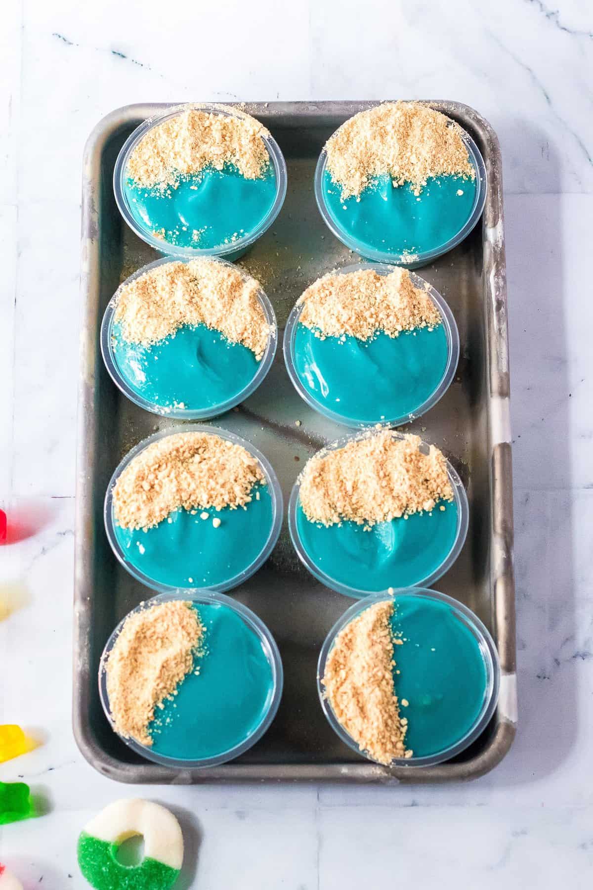 Overhead image of blue pudding shots with graham cracker crumbs on top
