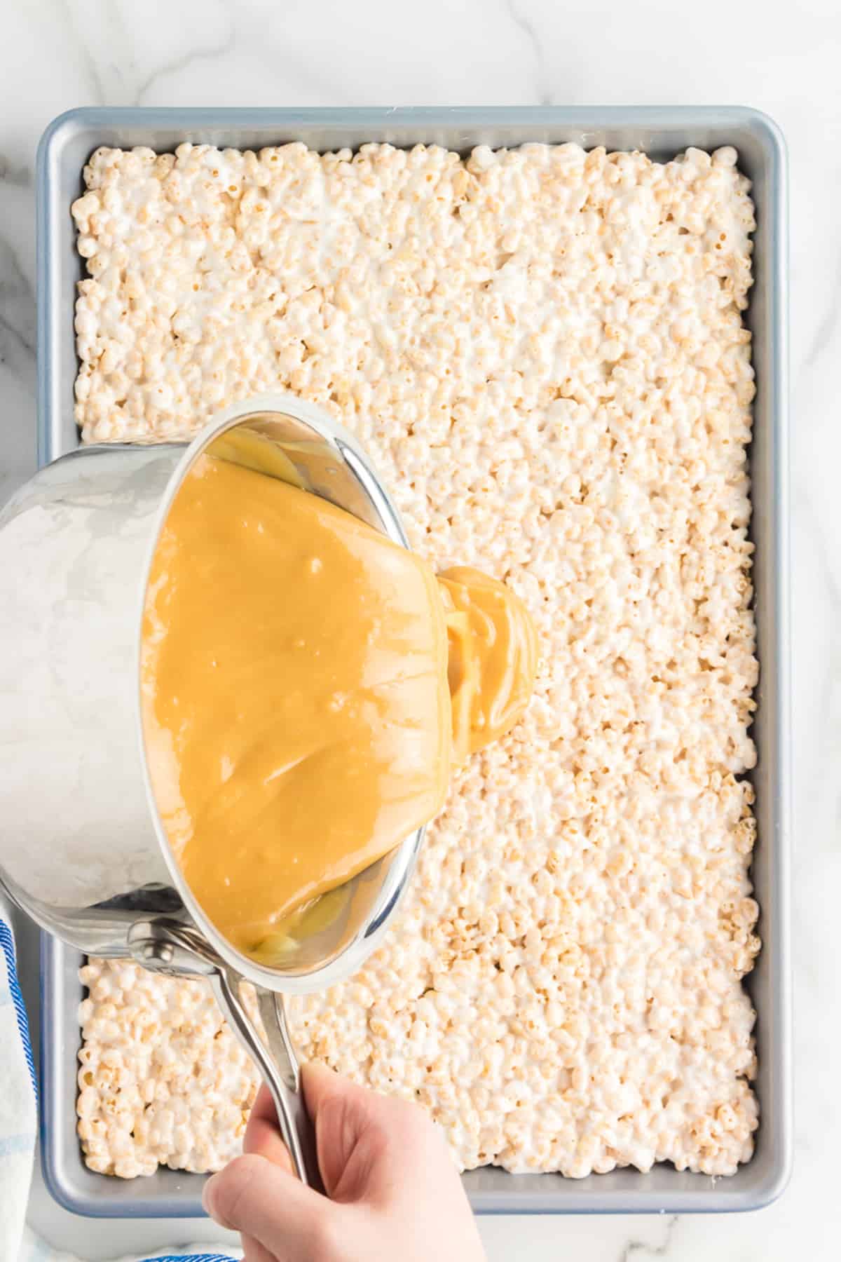 Pouring caramel sauce over rice krispie treats