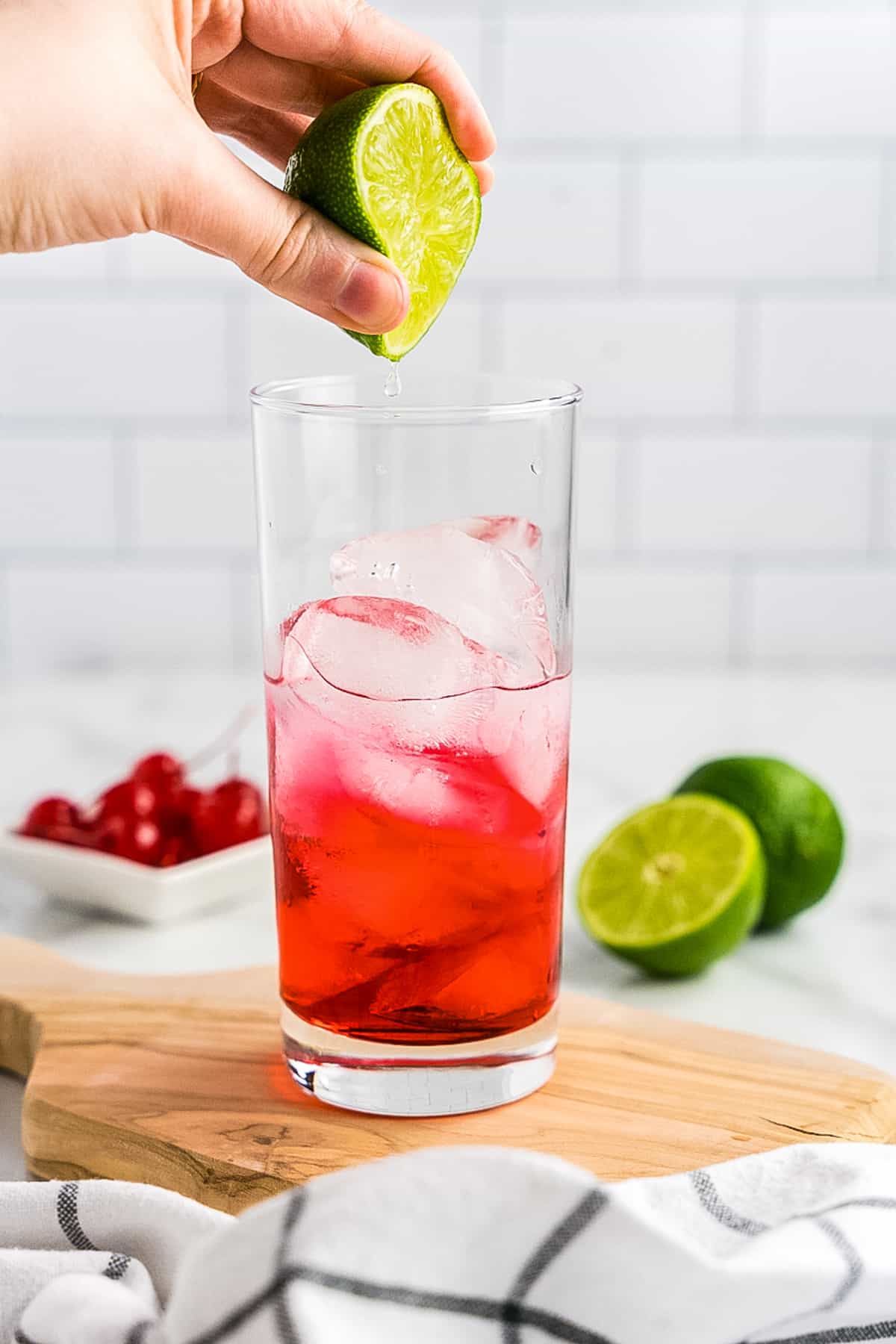 Squeezing lime juice into tall cocktail glass