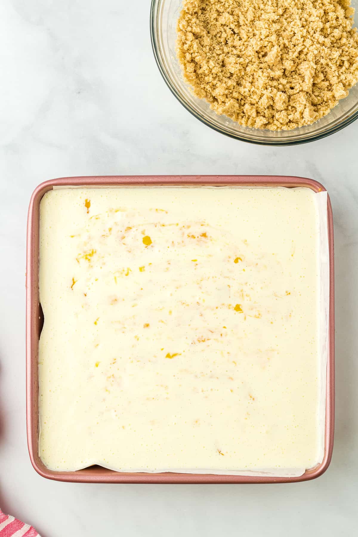 Cheesecake layer in square baking dish with chopped peaches