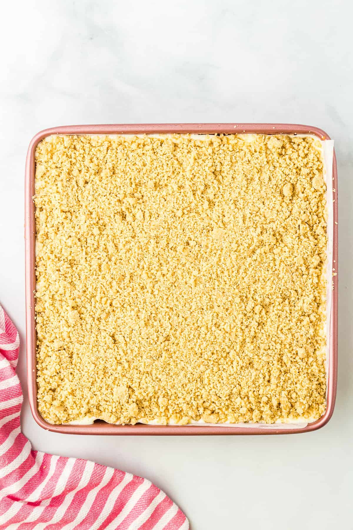 Crumble in mixing bowl on top of cheesecake bars in pan