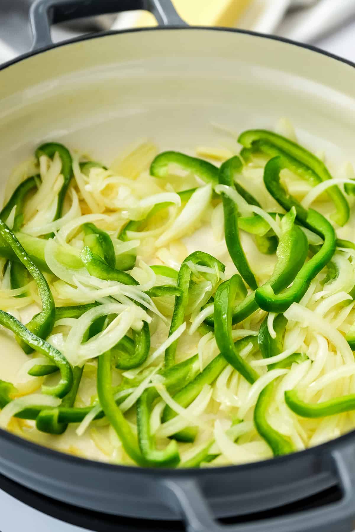 Skillet with thinly cut green peppers and onions